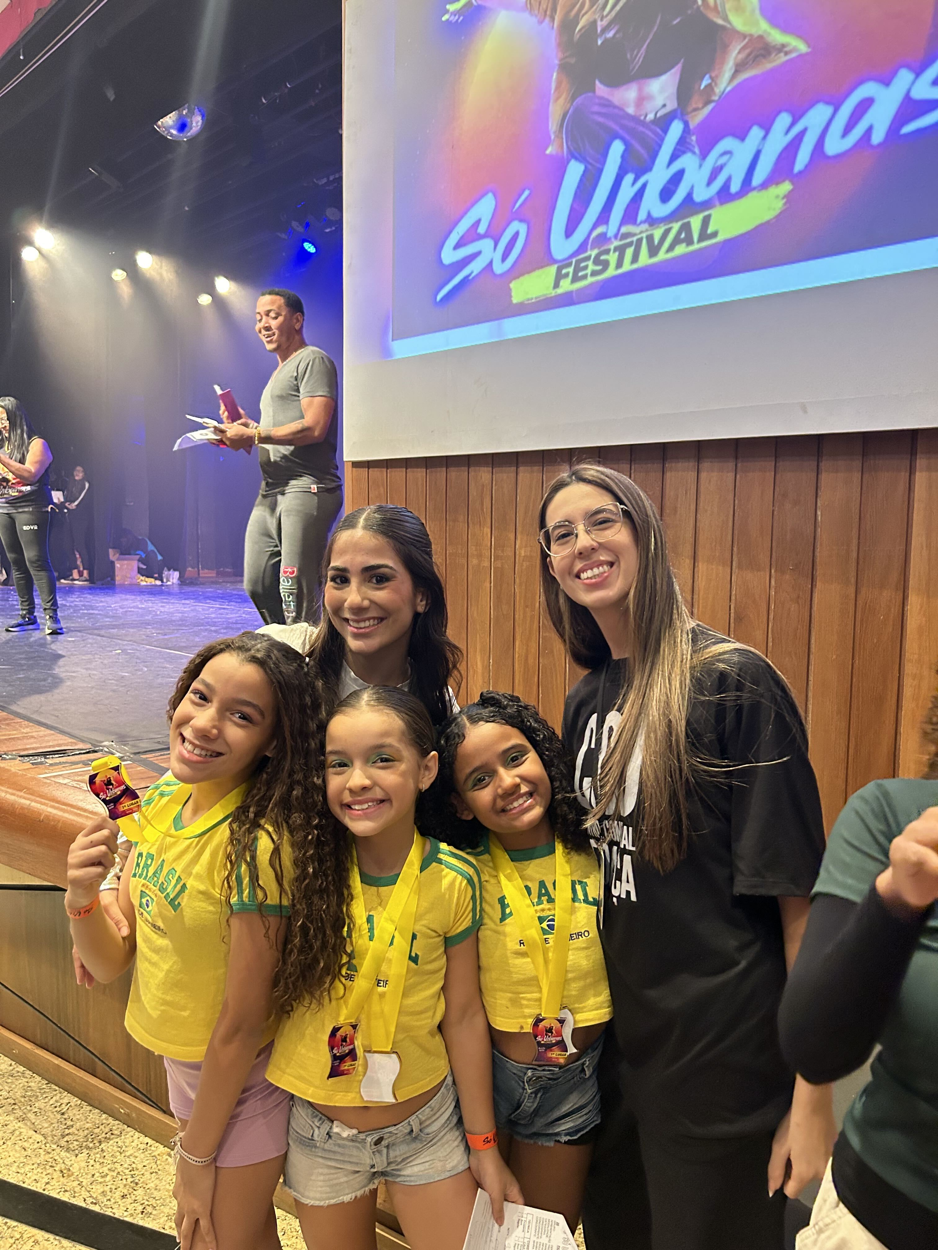 Maria com suas alunas de dança, camisetas do Brasil e medalhas na competição
